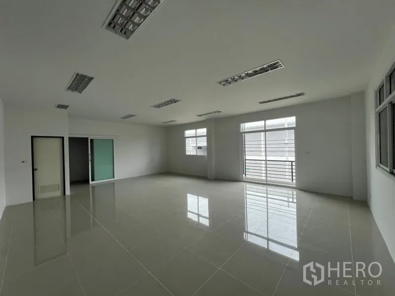 Warehouse for rent in Phra Samut Chedi, Samut Prakan - Large office area with sliding glass door, balcony-style window and glossy tiles.