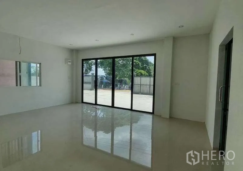 Warehouse for rent in Pathum Thani - Bright ground-floor office space featuring large sliding glass doors and glossy tiled flooring.