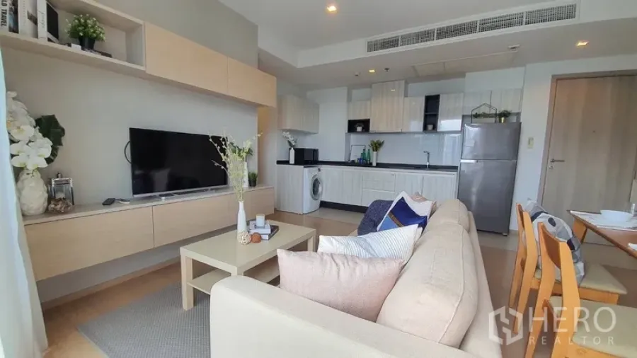 คอนโด ให้เช่าในWatthana, Bangkok - ห้องนั่งเล่นแบบเปิดโล่ง สว่าง พร้อมโซฟา ทีวี และชั้นบิลท์อิน ถัดจากครัวโมเดิร์น