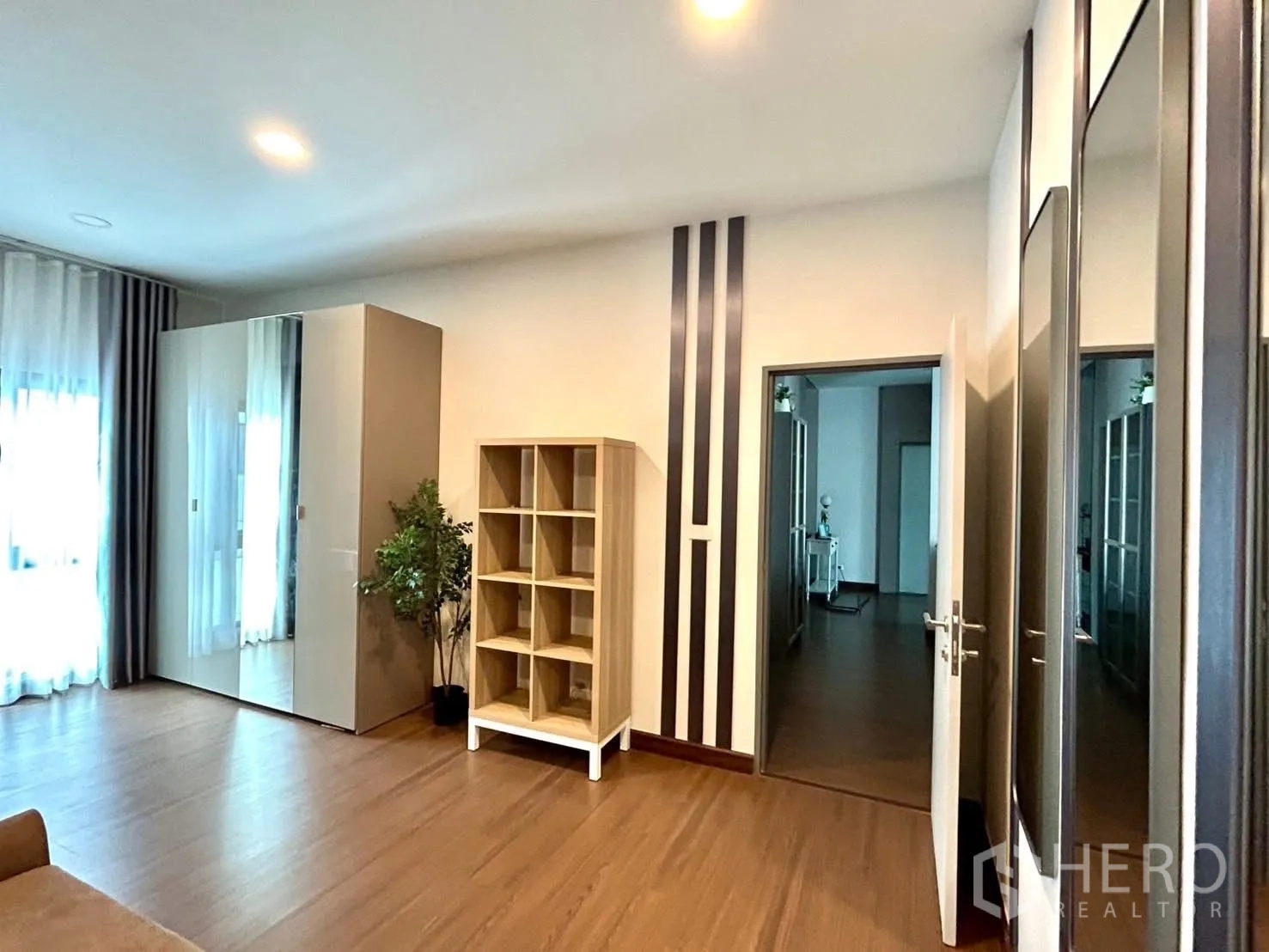 Detached House for rent in Bang Phli, Samut Prakan - Large bedroom with wardrobes, open shelving, and floor-to-ceiling curtains.