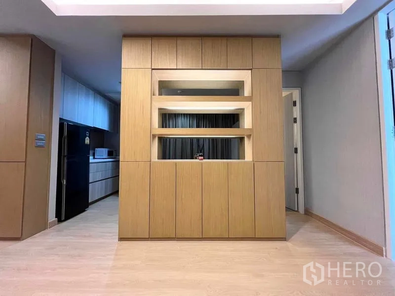 Condominium for rent or sale - Custom wood feature wall with display shelves and concealed storage facing the galley kitchen.