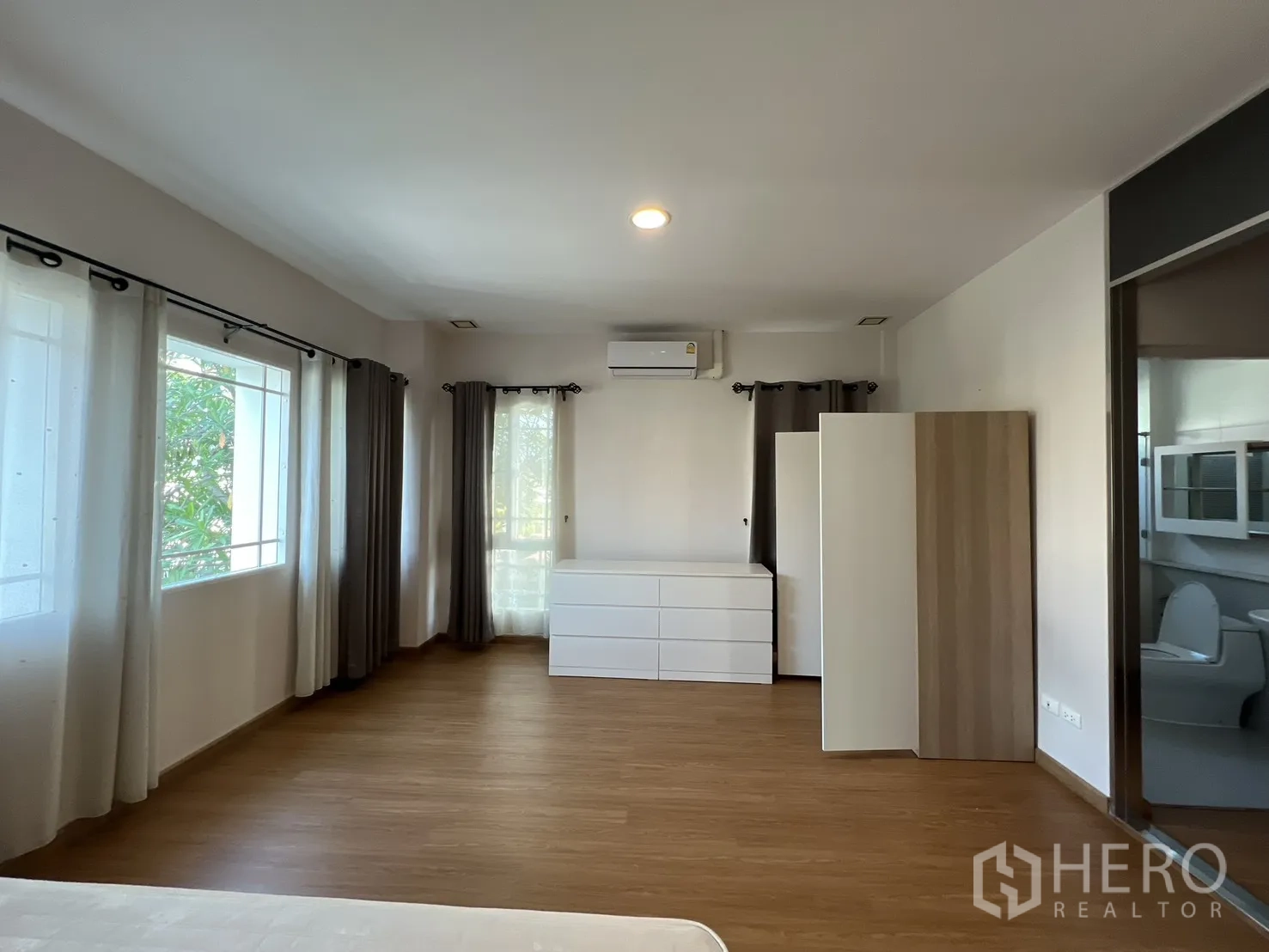 Detached House for rent in Bang Kapi, Bangkok - Bedroom view showing dresser, wardrobe, and wall-mounted air conditioner.