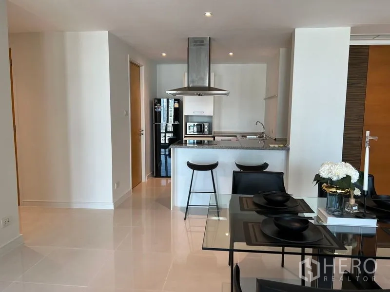 Condominium for rent in Watthana, Bangkok - Modern open kitchen with an island breakfast bar, stainless-steel range hood, and refrigerator.