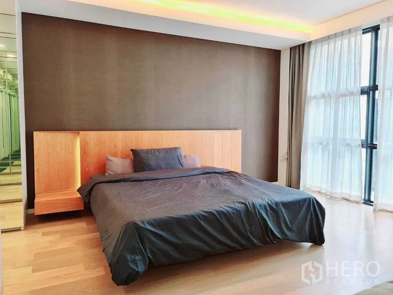 Condominium for rent in Watthana, Bangkok - Bright bedroom with king bed, wood headboard, mirrored wardrobes and floor-to-ceiling windows at Mode 61.