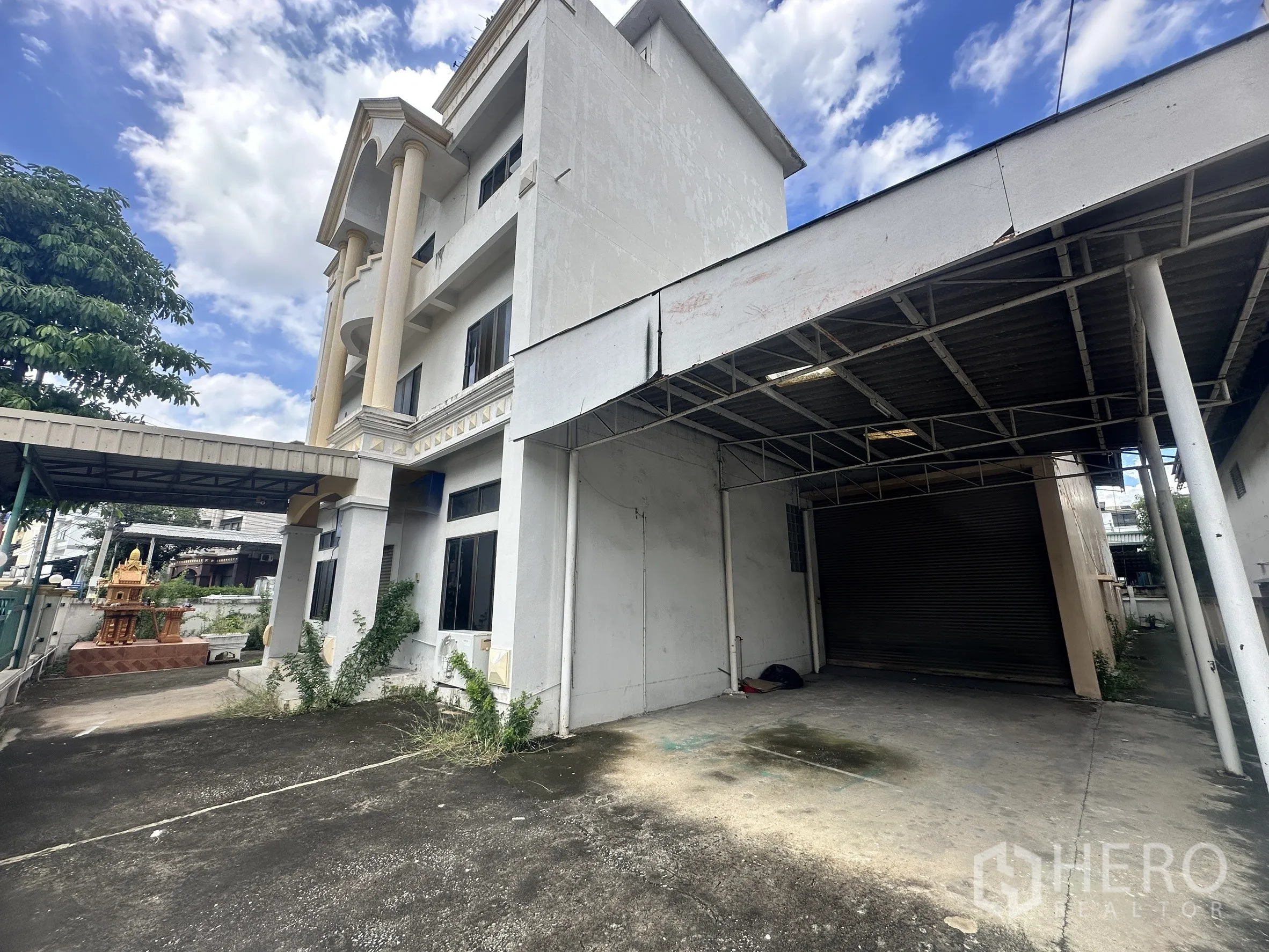 Factory for sale in Bang Bua Thong, Nonthaburi - Three-story office building with a covered loading bay and roller shutter.