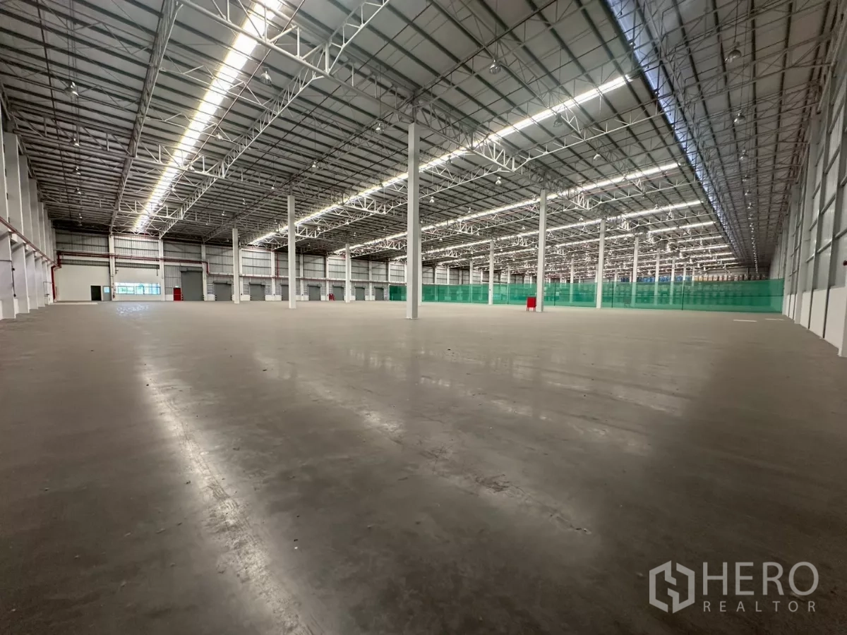 คลังสินค้า ให้เช่าในBang Phli, Samut Prakan - มุมมองภายในลึก แสดงช่องจัดเก็บยาวและตาข่ายนิรภัยสีเขียว