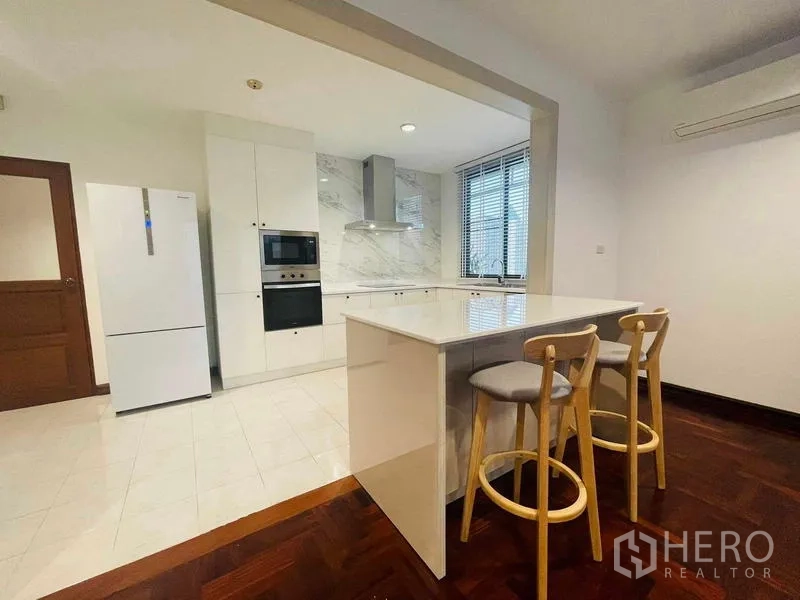 Condominium for rent - Modern white kitchen with marble backsplash and breakfast island with two stools.