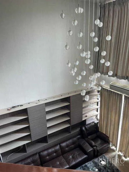 联排别墅 出租在Khlong Toei, Bangkok - 挑高客厅，皮沙发、壁柜与串珠吊灯，从楼上俯拍
