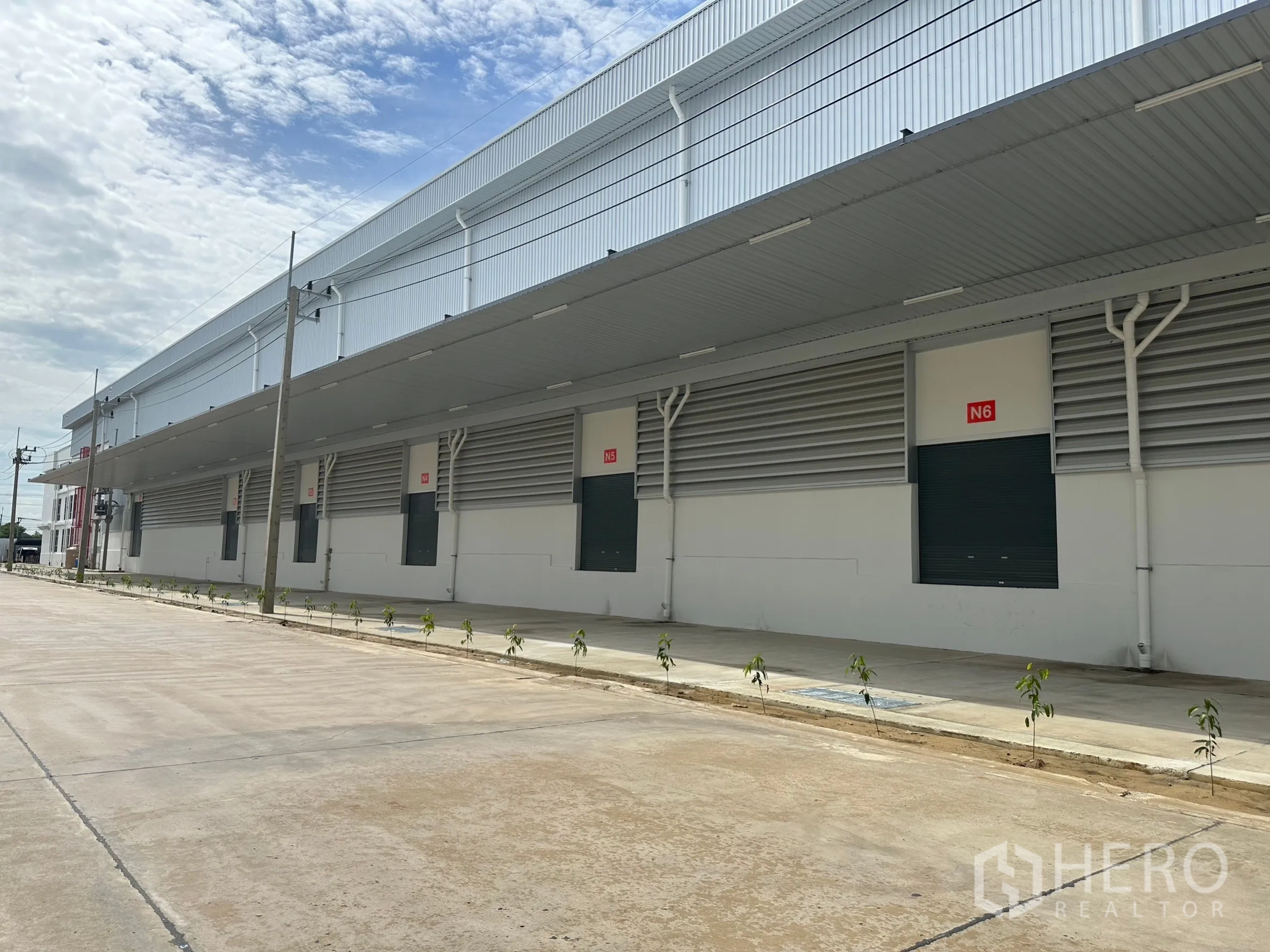 工厂 出租在Khlong Luang, Pathum Thani - 现代仓库立面，带长雨棚、多个装卸月台与卷帘门。