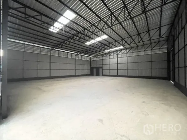 Warehouse for rent in Lat Phrao, Bangkok - Spacious warehouse interior with high steel truss roof, skylights and smooth concrete floor