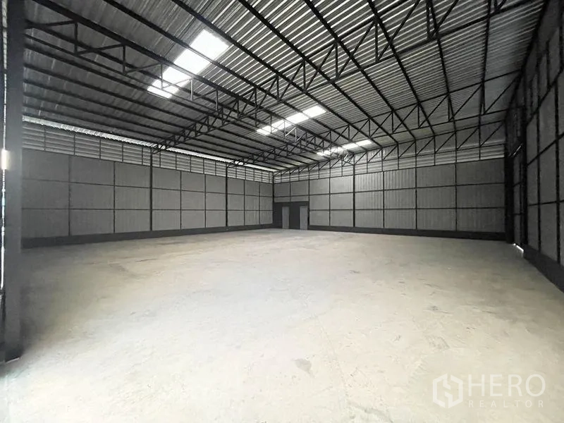 Warehouse for rent in Lat Phrao, Bangkok - Spacious warehouse interior with high steel truss roof, skylights and smooth concrete floor
