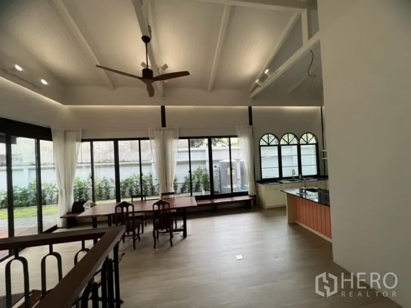 独立式住宅 出租在Ratchathewi, Bangkok - 挑高客厅，拱形屋顶、吊扇、大窗与开放式厨房。