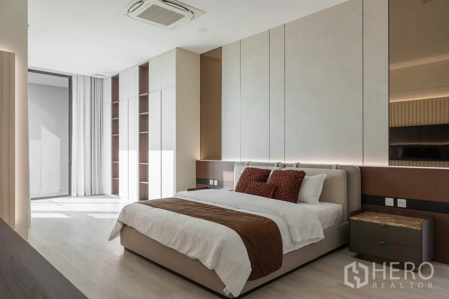 Detached House for rent in Saphan Sung, Bangkok - Spacious master bedroom with king bed, paneled accent wall, and fitted wardrobes opening to a balcony.