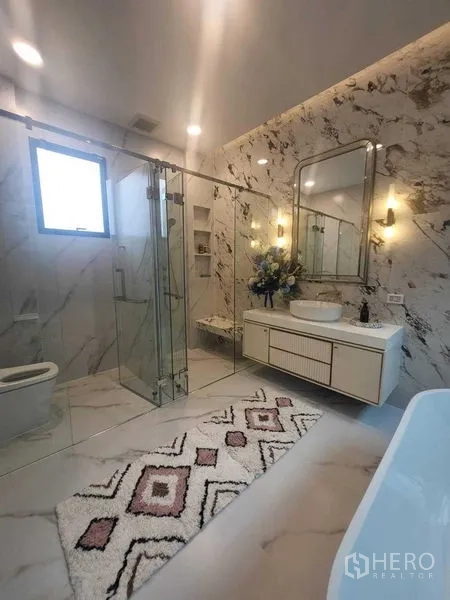 Detached House for rent in Saphan Sung, Bangkok - Marble-clad bathroom with glass shower, illuminated vanity and bathtub.
