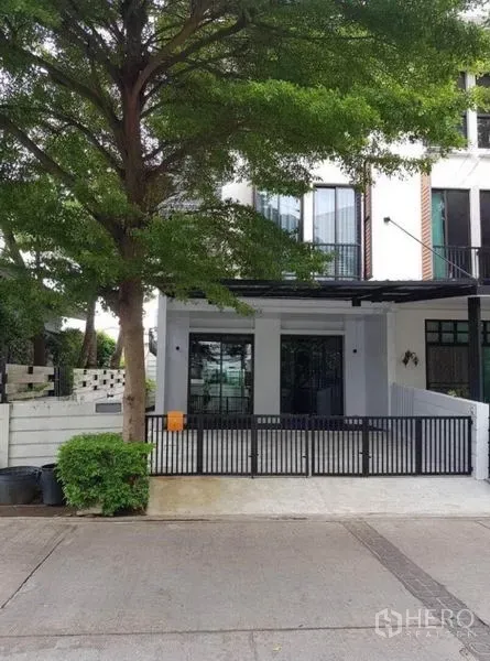 Townhouse for rent in Suan Luang, Bangkok - Front view of the townhouse exterior with a black gate and covered parking.