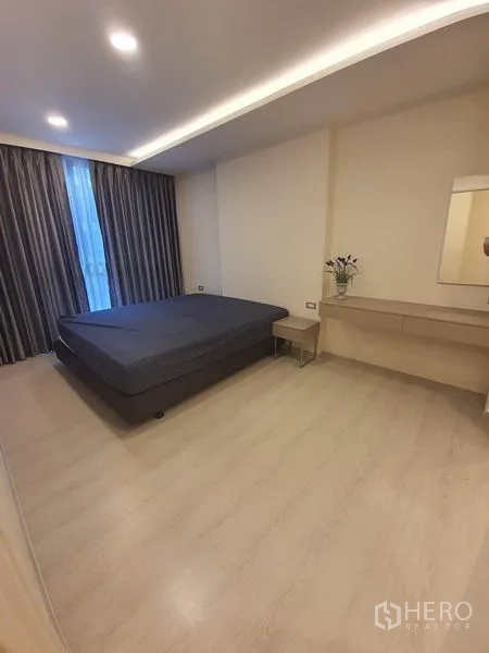 Condominium for rent in Khlong Toei, Bangkok - Master bedroom with large bed, wood floors, recessed ceiling lights and blackout curtains.