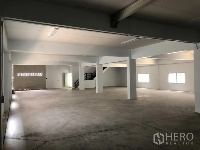 Factory for rent in Pak Kret, Nonthaburi - Ground floor warehouse bay with roller shutter door, columns and windows.
