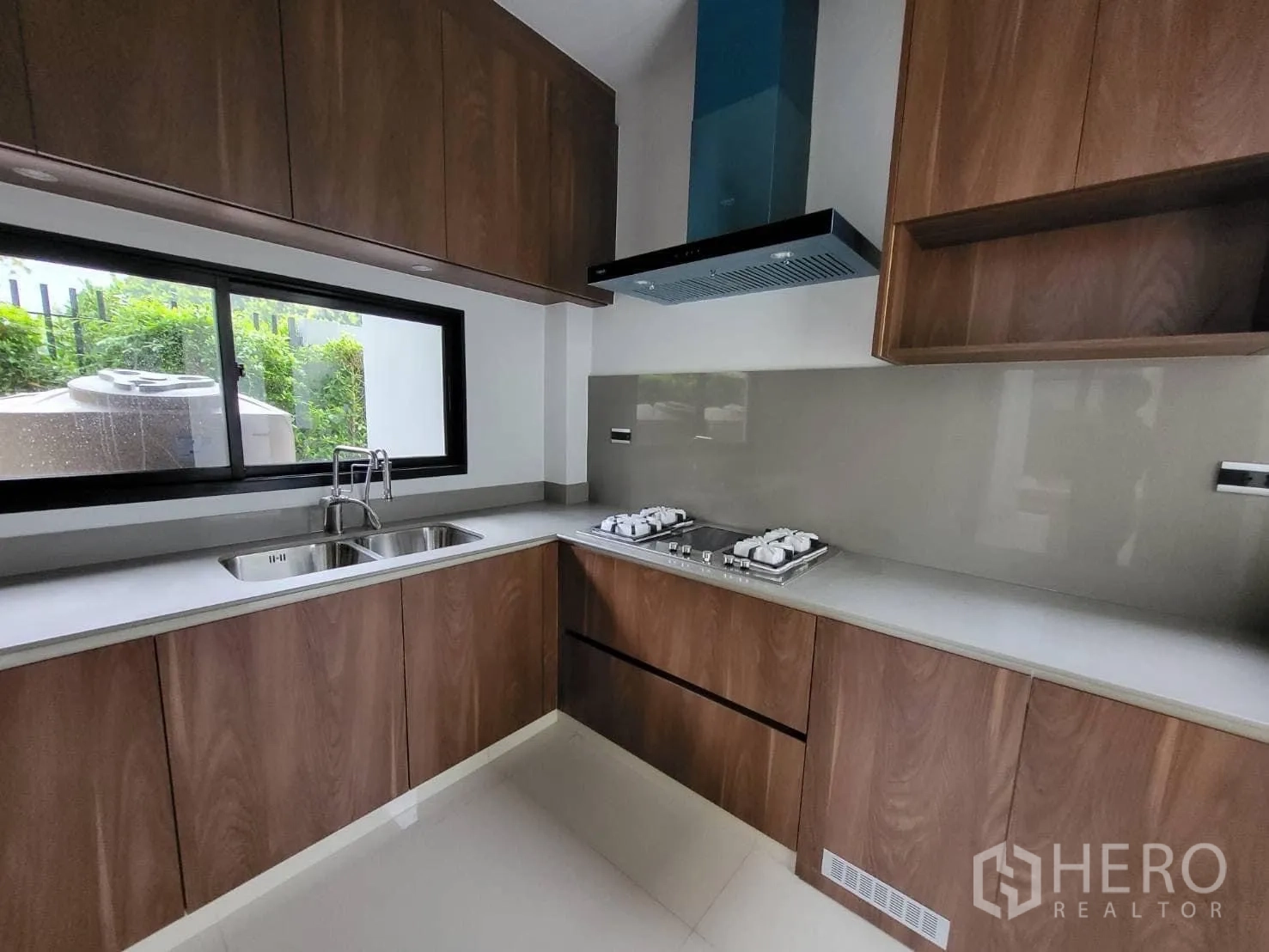 Detached House for rent - Separate Thai kitchen with wood cabinetry, twin sink, window and gas hobs with range hood.
