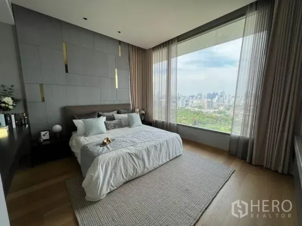 公寓 出租在Bang Rak, Bangkok - 主卧设整面落地窗，俯瞰公园与城市天际线全景。