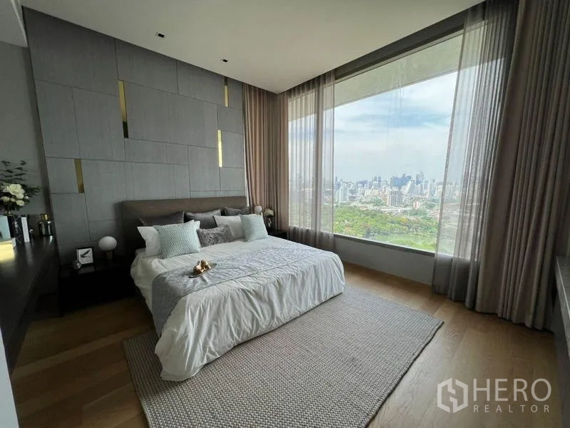 公寓 出租在Bang Rak, Bangkok - 主卧设整面落地窗，俯瞰公园与城市天际线全景。
