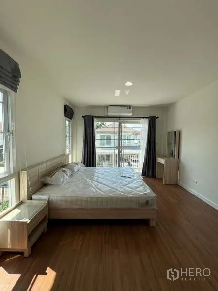 Detached House for rent in Bang Kapi, Bangkok - Bright master bedroom with balcony doors and a king bed.