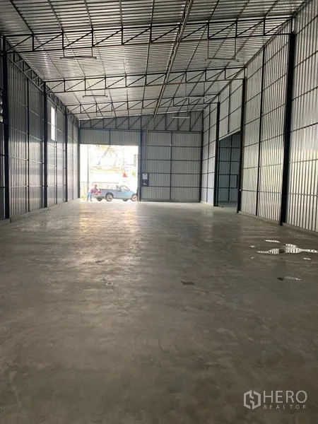 Warehouse for rent in Khan Na Yao, Bangkok - Open-plan warehouse bay looking toward the wide entrance with truck access and metal-clad walls.