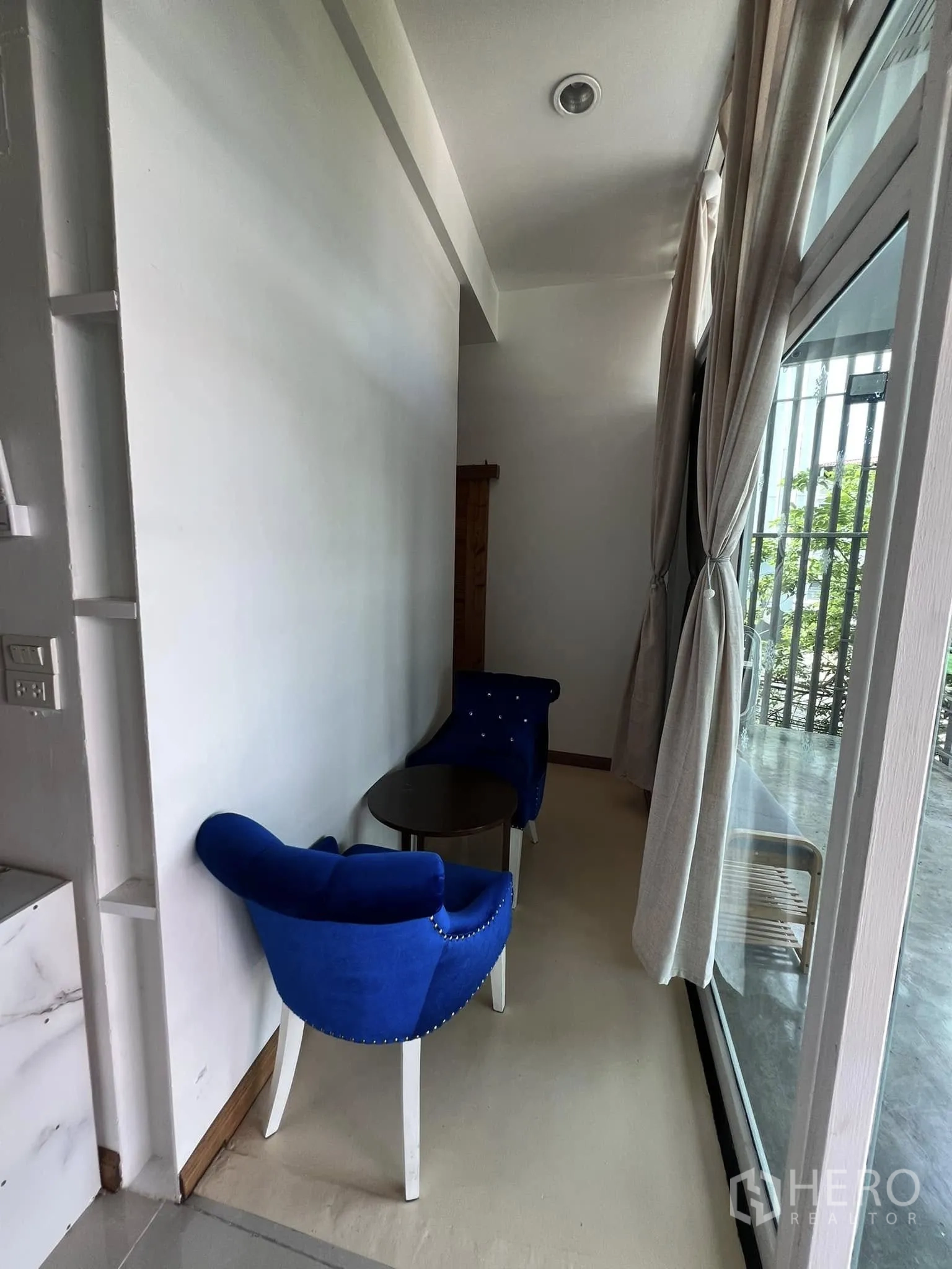 零售空间 for rent in Lat Phrao, Bangkok - 窗边小型等候区，两把蓝色椅子与小圆桌。