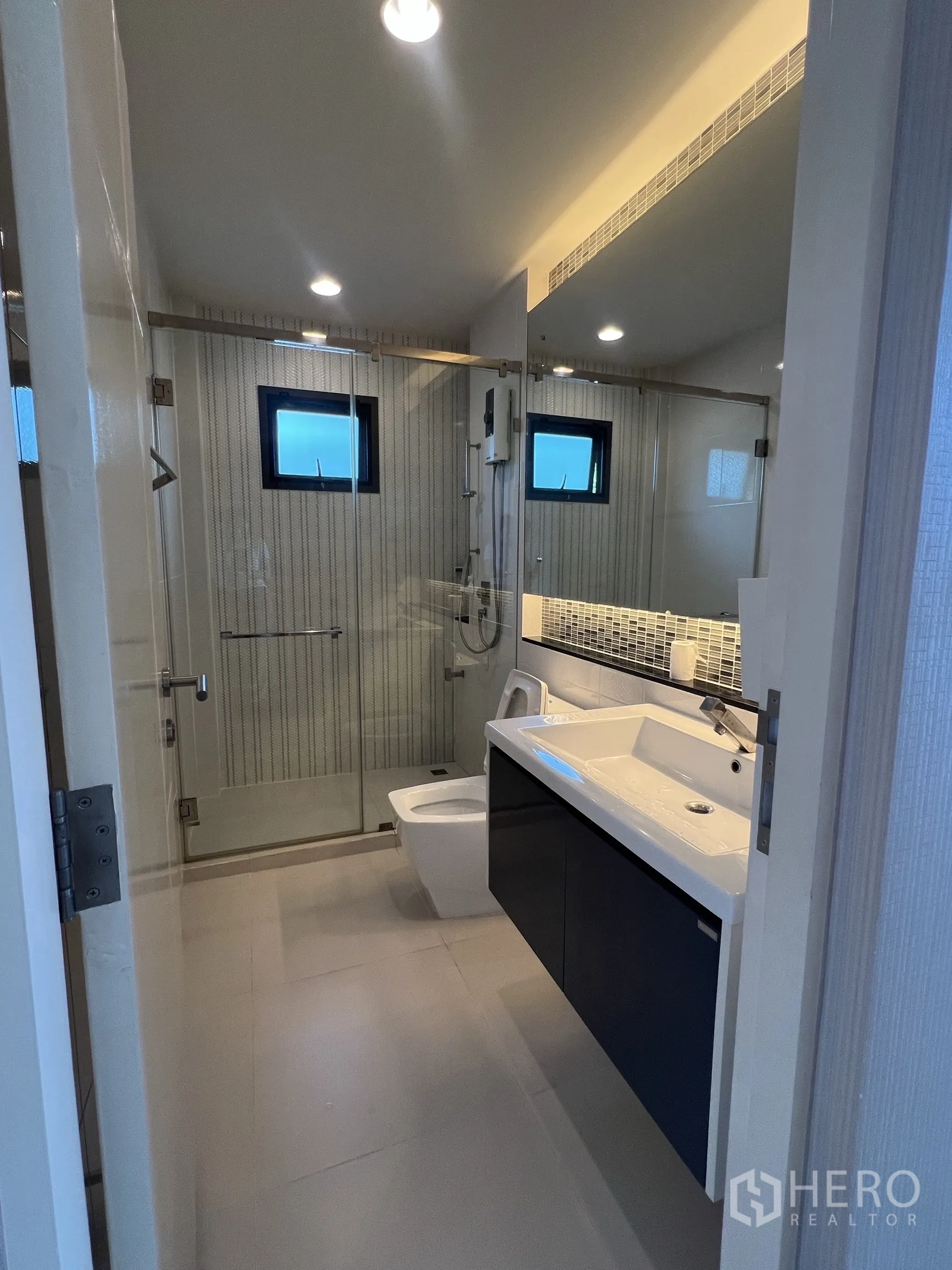 Detached House for rent in Bang Kapi, Bangkok - Modern bathroom with glass-enclosed shower, floating vanity and toilet.