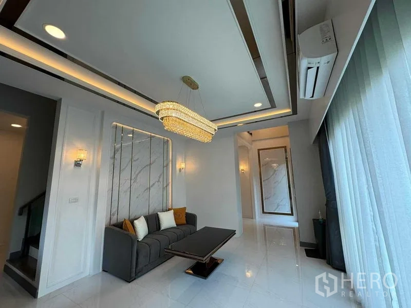 บ้าน ให้เช่าหรือขายในBang Na, Bangkok - อีกมุมของห้องรับแขก โคมไฟระย้า โซฟา และหน้าต่างสูงเต็มบาน
