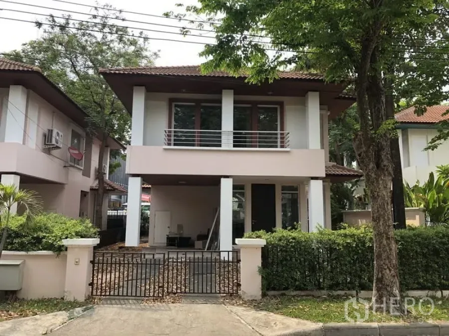 Detached House for sale in Wang Thonglang, Bangkok - Two-storey detached house with balcony, gated carport, and mature trees at the front.