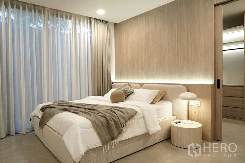 Detached House for rent in Saphan Sung, Bangkok - Guest bedroom with wood accent wall, sheer curtains and sliding door to a walk-in closet.