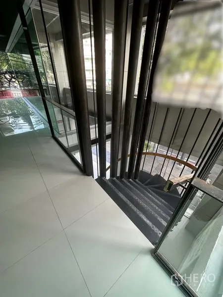 零售空间 出租在Bang Rak, Bangkok - 室内楼梯平台，金属栏杆与落地玻璃窗。