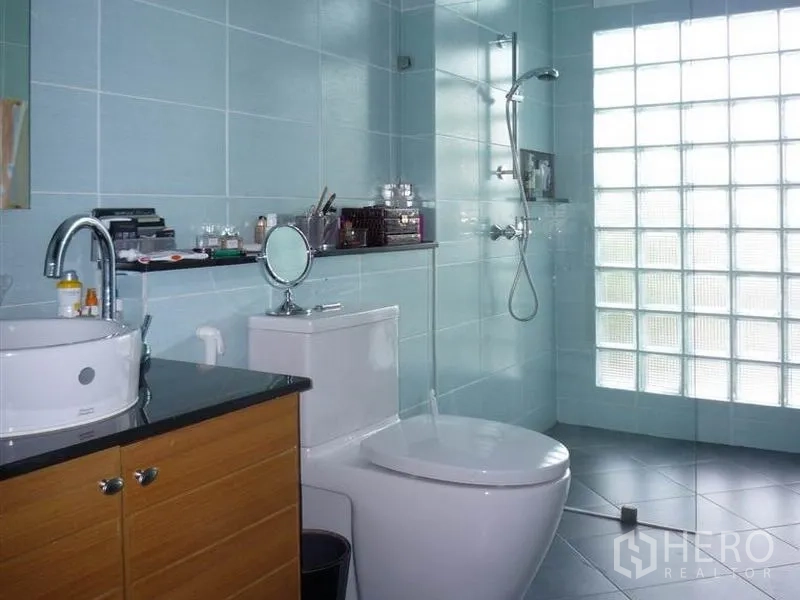 Detached House for rent in Khan Na Yao, Bangkok - Light blue tiled bathroom with glass-block shower, toilet and vanity
