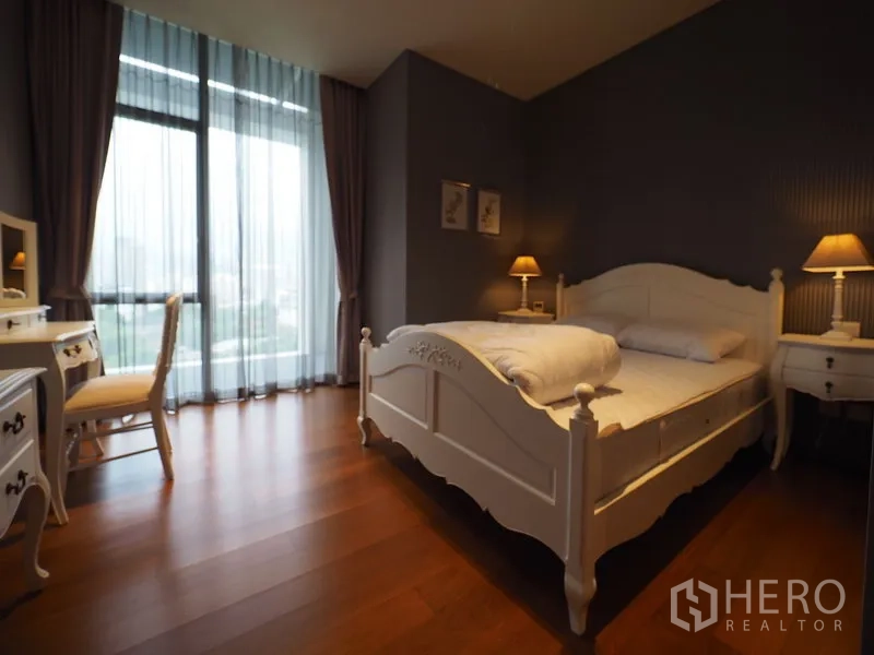 Condominium for rent in Sathon, Bangkok - Second bedroom with white bed frame, vanity desk and large windows.