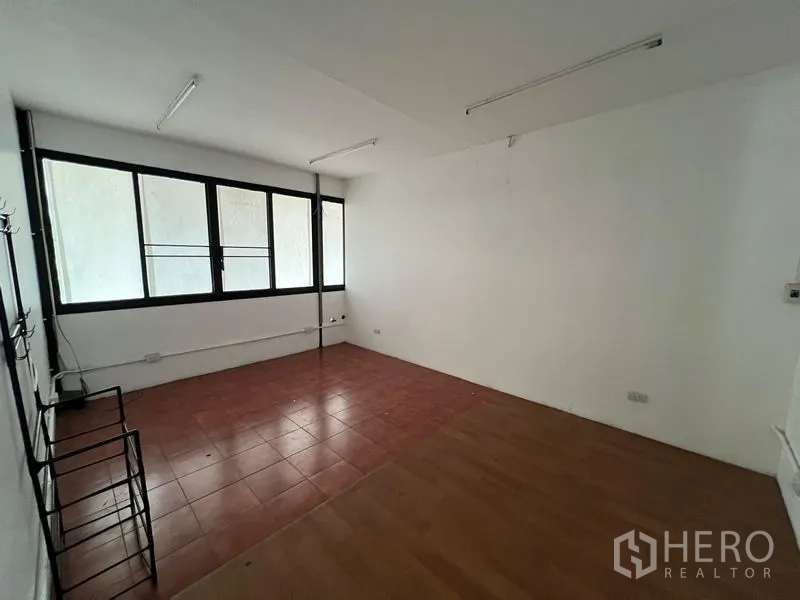 Warehouse for rent in Saphan Sung, Bangkok - Small office room with windows and fluorescent lighting inside the warehouse.