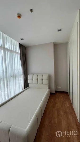 公寓 出租在Bang Na, Bangkok - 第三卧室布置单人床、嵌入式衣柜与转角高窗配窗帘。
