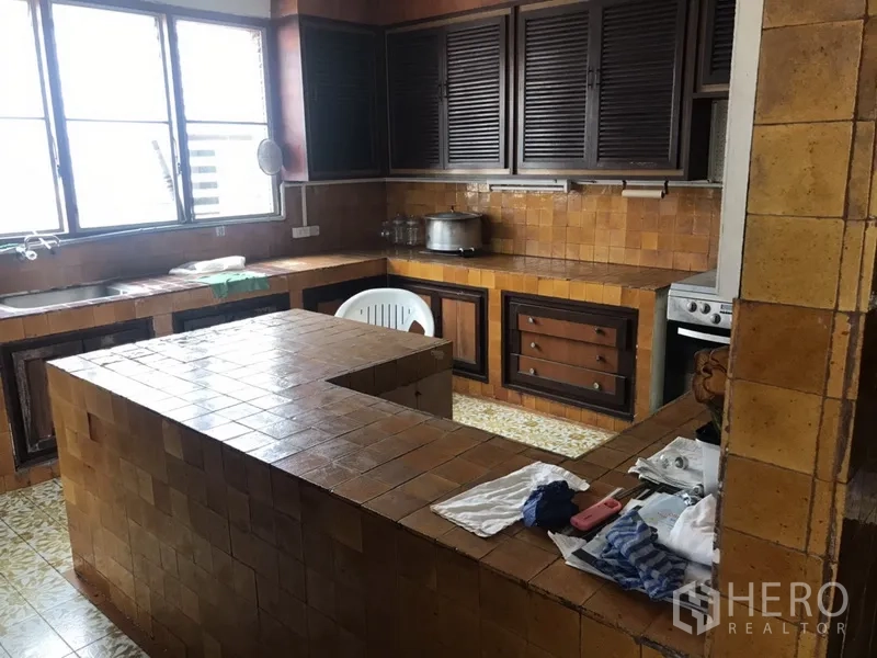 Home Office for rent in Khlong Toei, Bangkok - Vintage tiled kitchen with a U-shaped island, louvered cabinets and wide windows.