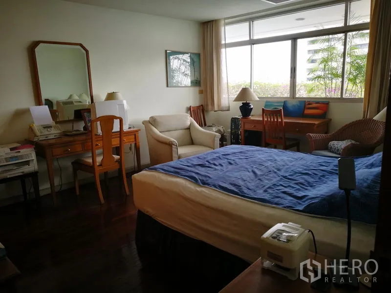 Condominium for rent or sale in Watthana, Bangkok - Bright bedroom with large window, desk and cozy seating area.