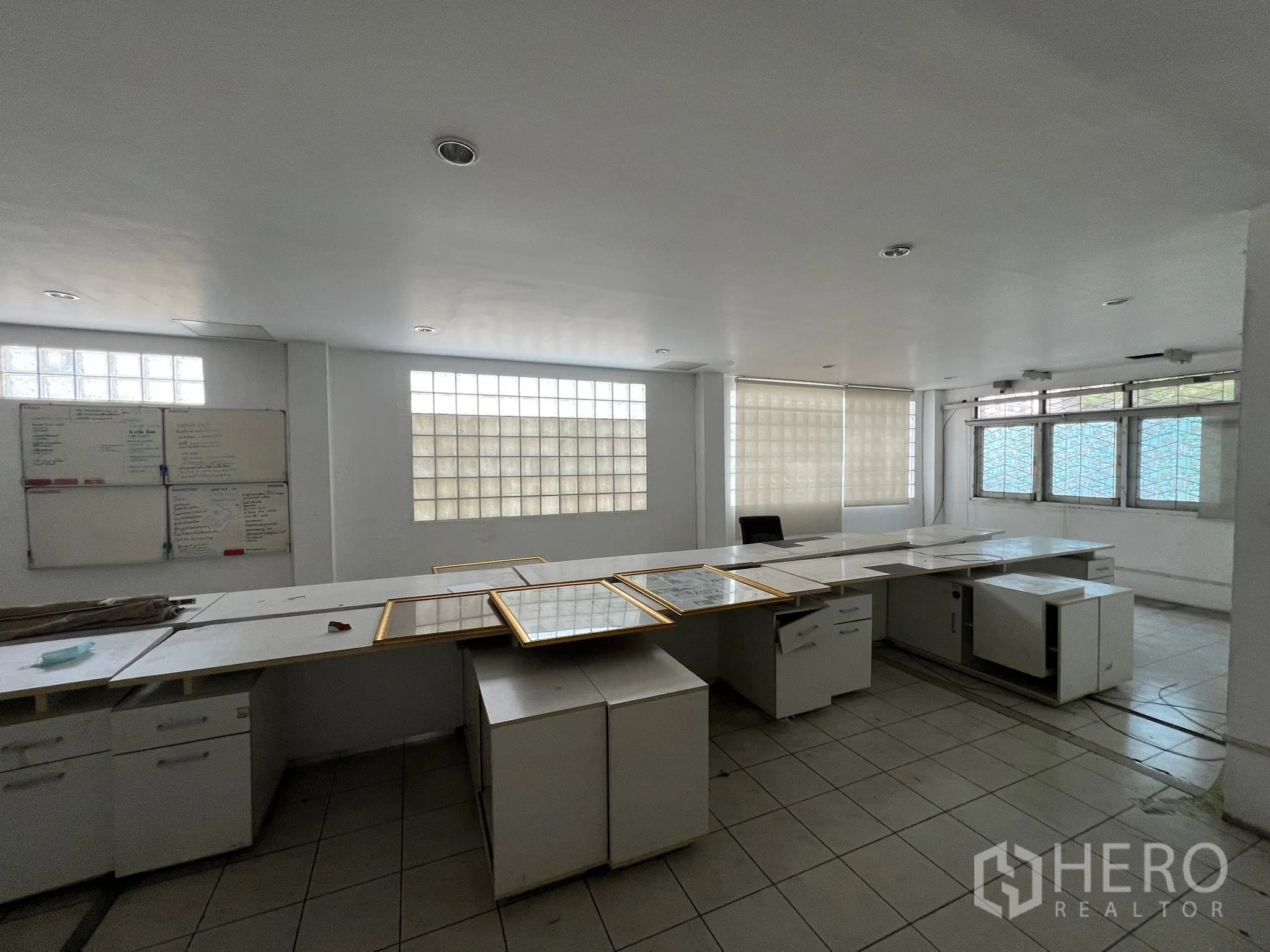 Shophouse for rent in Khlong Toei, Bangkok - Bright office floor with built-in desks and glass-block windows.