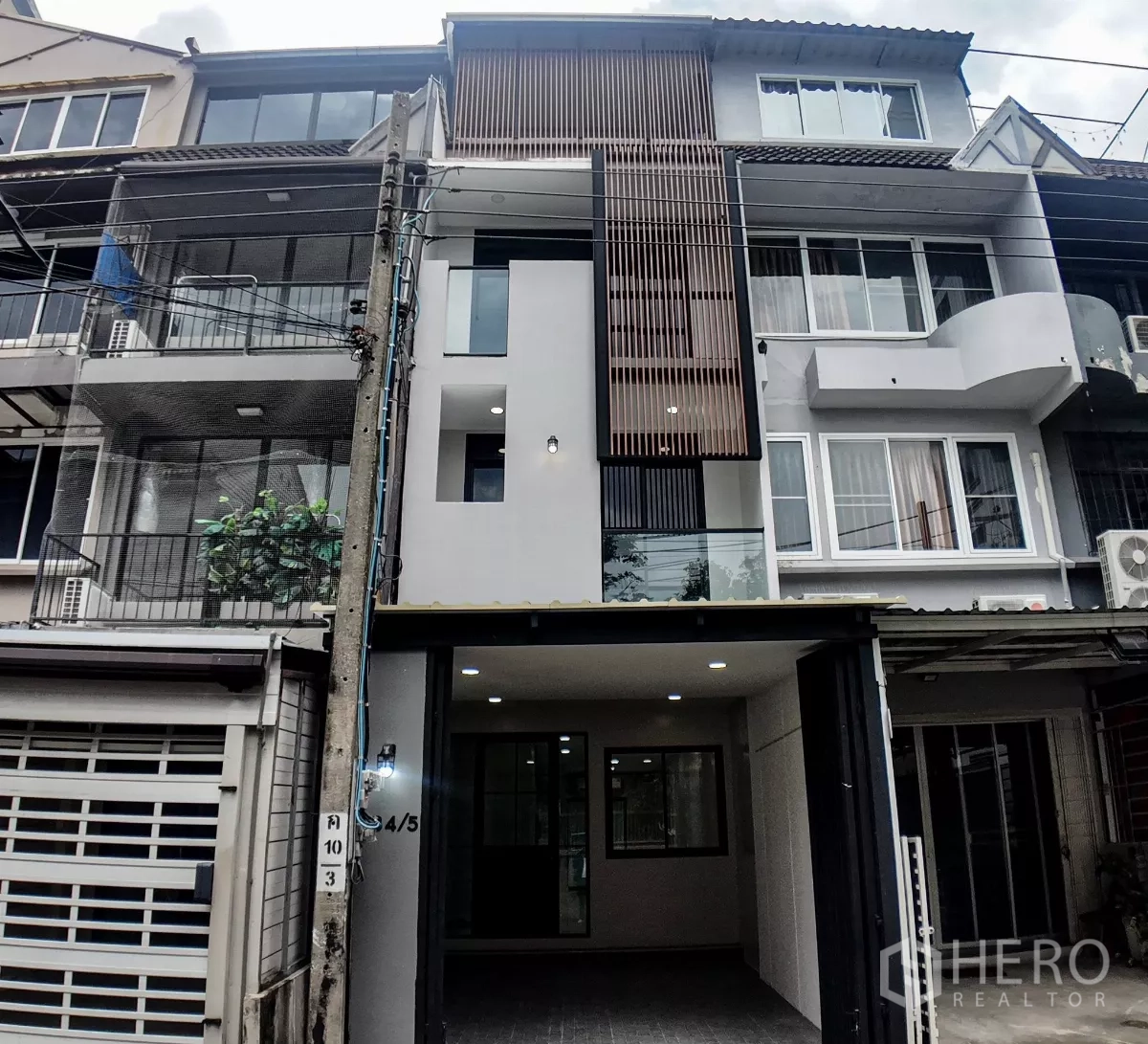 联排别墅 出售在Watthana, Bangkok - 现代四层联排别墅外观，立面木格栅设计，带有遮雨车位，位于素坤逸片区。