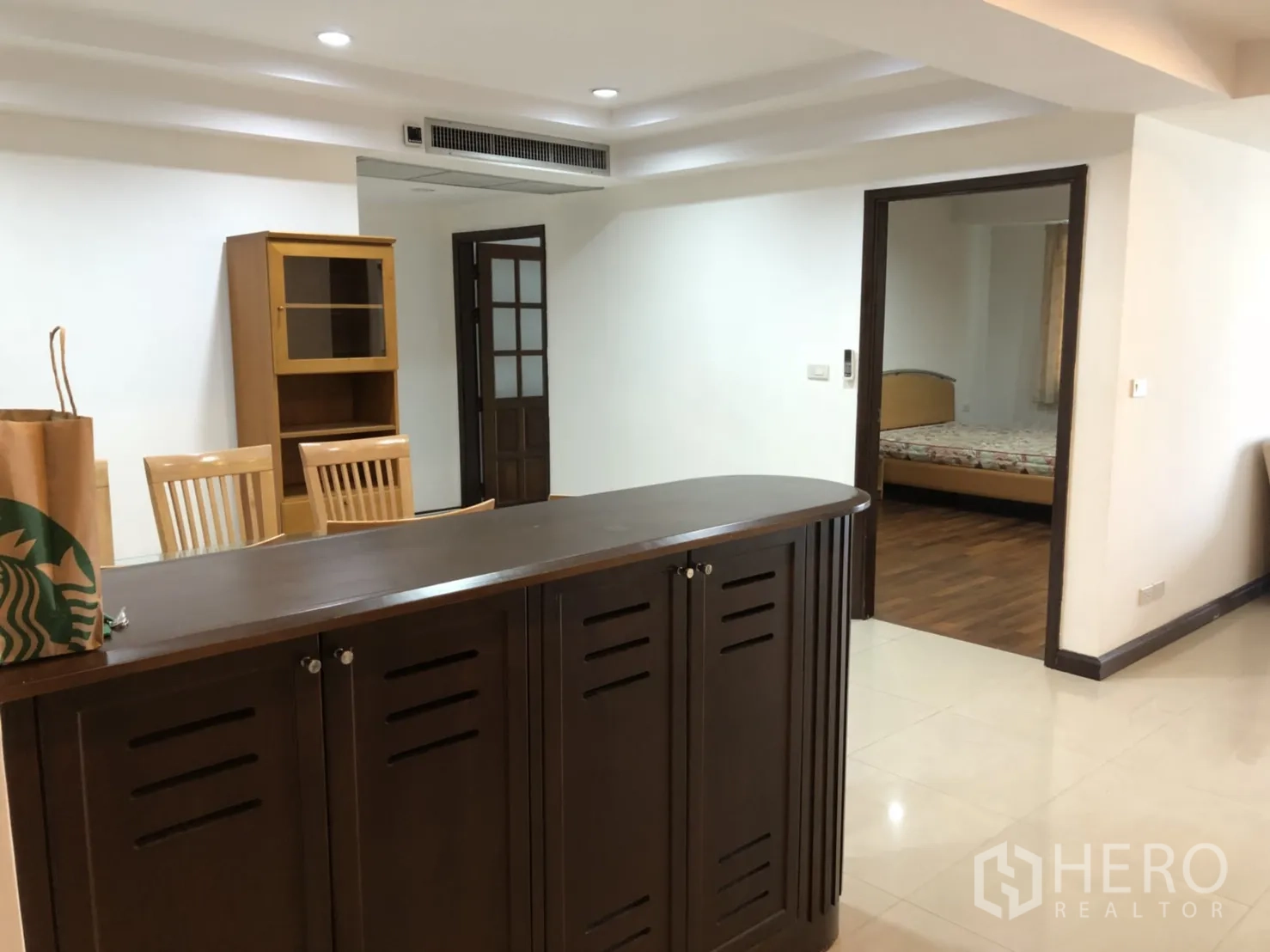 Condominium for rent in Watthana, Bangkok - Foyer with bar-style cabinet, dining chairs and doorway to a bedroom.
