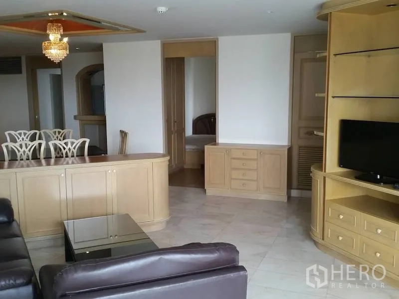 公寓 出租在Watthana, Bangkok - 宽敞客厅，皮沙发、内置电视柜与水晶吊灯，艾卡迈公寓。