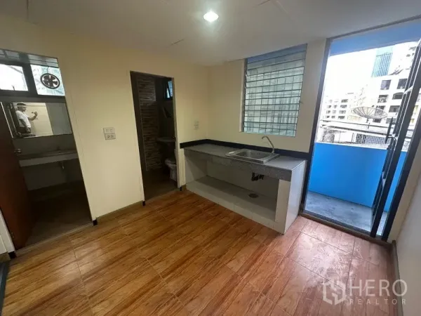 Office Space for rent in Bang Rak, Bangkok - Pantry area with sink and tiled floor, opening to a balcony with city views and an adjacent restroom.
