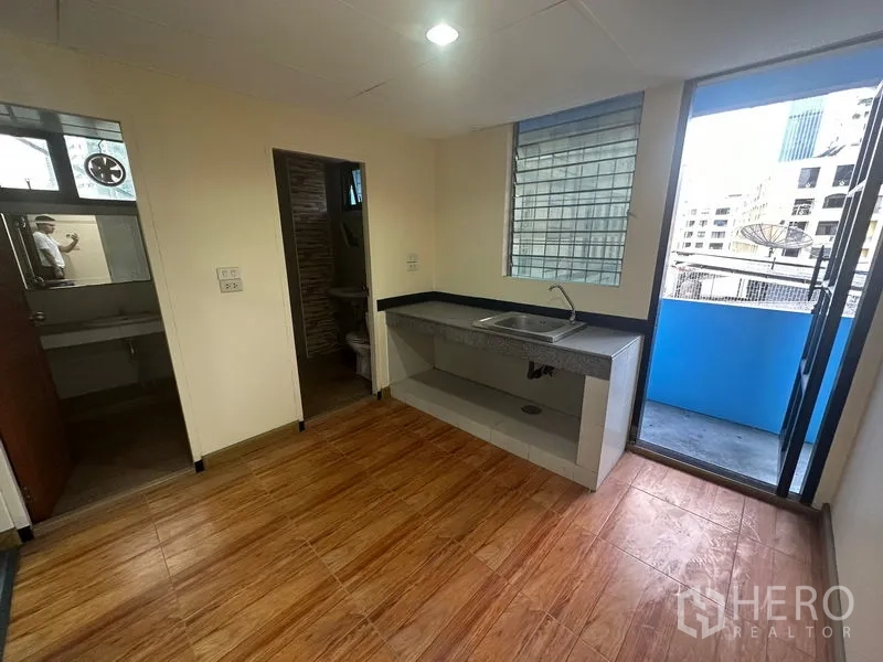 Office Space for rent in Bang Rak, Bangkok - Pantry area with sink and tiled floor, opening to a balcony with city views and an adjacent restroom.