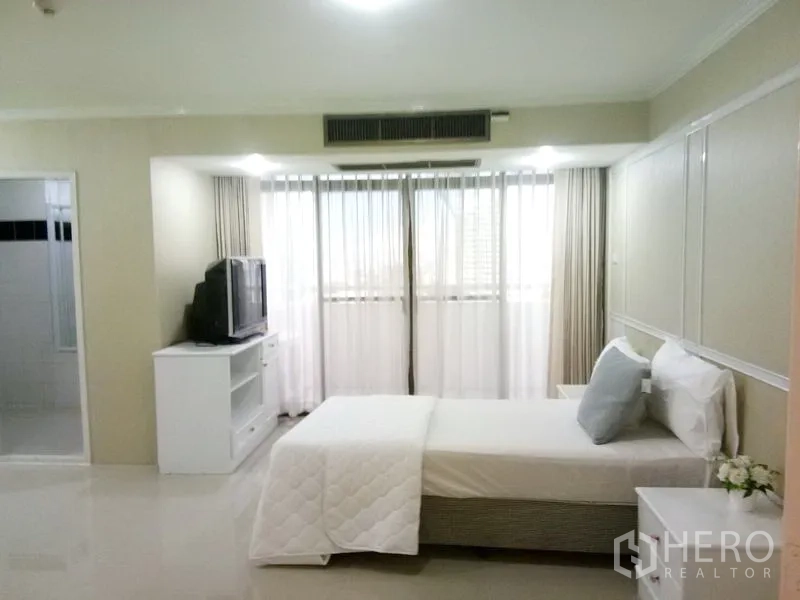 Condominium for rent in Watthana, Bangkok - Second bedroom with balcony access, sheer curtains and TV console.