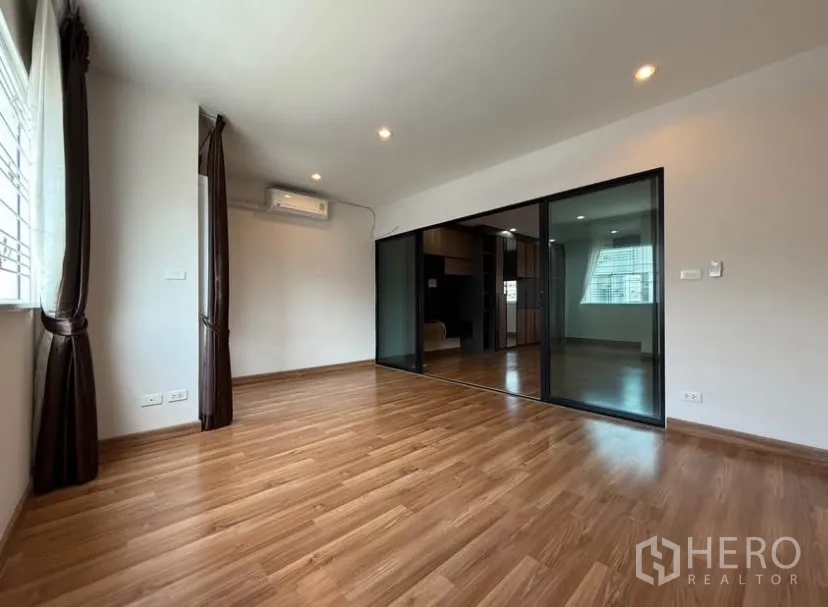 Townhouse for rent in Suan Luang, Bangkok - Bedroom opening to another room via full-height black-framed sliding doors.
