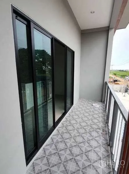 Warehouse for rent in Pathum Thani - Upper-level balcony with sliding glass doors and patterned floor tiles overlooking the yard.