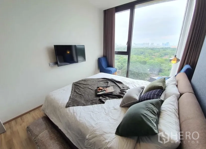 คอนโด for rent in Chatuchak, Bangkok - ห้องนอนมีหน้าต่างบานใหญ่ เตียงนุ่ม เก้าอี้สองตัว และทีวีติดผนัง