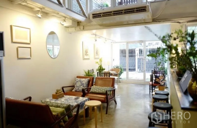 Townhouse for rent in Khlong Toei, Bangkok - Open living lounge with leather seating, large windows and greenery.