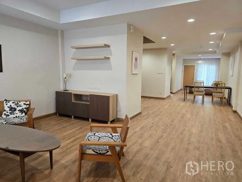 联排别墅 出租在Bang Na, Bangkok - 客厅配休闲椅、电视柜、置物架与木地板。